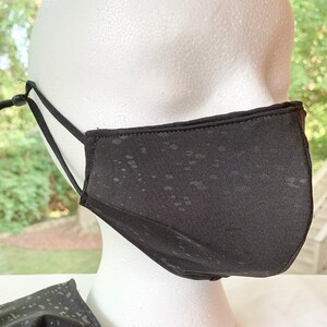 May include: Two black face masks with adjustable straps. The masks have a subtle speckled pattern and are made of a soft, breathable fabric.