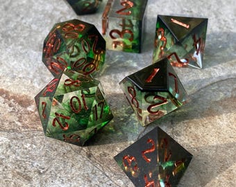 May include: Set of eight green and copper dice with a clear, translucent finish. The dice are numbered with copper colored numerals.