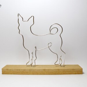 May include: A silver wire sculpture of a dog standing on a wooden base. The base is labeled "Oak Base".