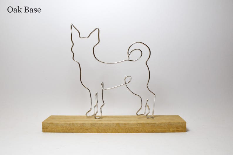 May include: A silver wire sculpture of a dog standing on a wooden base. The base is labeled "Oak Base".