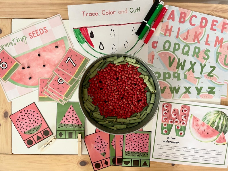 May include: A set of educational activities for kids featuring a watermelon theme. The set includes a counting activity, a tracing and coloring activity, an alphabet activity, and a shape matching activity. The activities are designed to help children learn about numbers, letters, shapes, and colors.