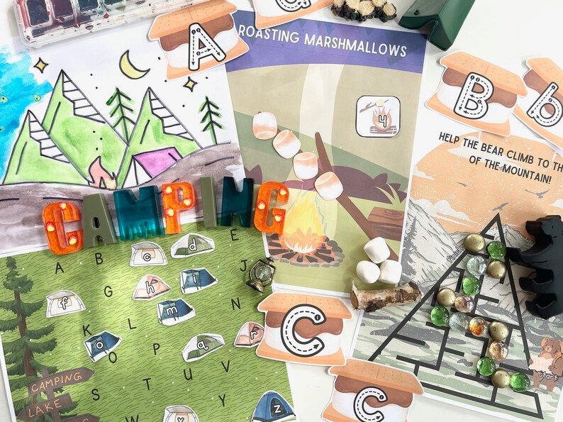 May include: A set of colorful camping-themed educational materials for kids. The set includes a printable coloring page with a camping scene, a printable alphabet chart with camping-themed images, a printable game board with a bear climbing a mountain, and a set of letter tiles that spell out the word "CAMPING".