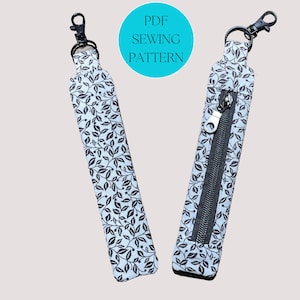 May include: A PDF sewing pattern for a key chain with a zippered pocket. The key chain is made of fabric with a black and white leaf pattern. The pattern is available for download.