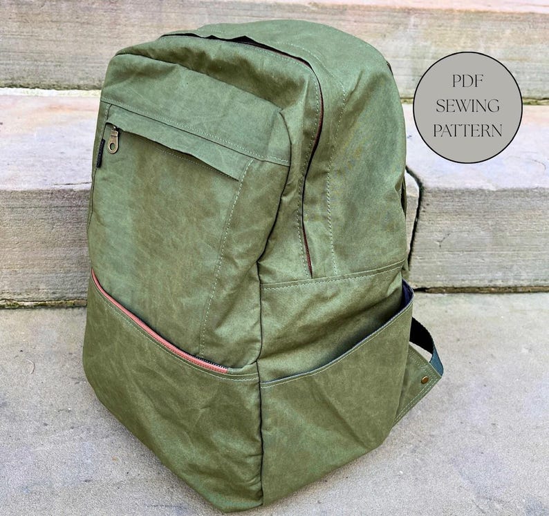May include: A green backpack with a front pocket and a side pocket. The backpack has a zip closure and a pink zip pull. The text "PDF SEWING PATTERN" is in a circle on the right side of the backpack.
