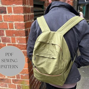 May include: An olive green backpack with multiple pockets and adjustable straps. The backpack features a front pocket, side pockets, and a top handle. The text "PDF SEWING PATTERN" is in a grey circle on the left side of the image.
