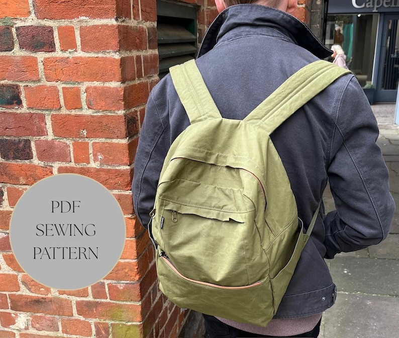 May include: An olive green backpack with multiple pockets and adjustable straps. The backpack features a front pocket, side pockets, and a top handle. The text "PDF SEWING PATTERN" is in a grey circle on the left side of the image.