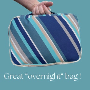 May include: A striped overnight bag with blue, teal, beige, and white stripes. The bag has a zipper closure and a handle.