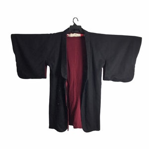 May include: A black and burgundy kimono with long sleeves and a front closure. The kimono is made of a soft, lightweight fabric.