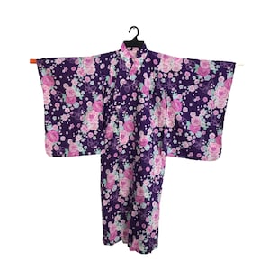 Puede incluir: Un kimono con estampado floral morado y rosa con un diseño tradicional japonés.