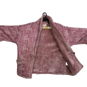 May include: A pink robe with a geometric pattern. The robe is made of a soft, plush fabric and has a shawl collar.