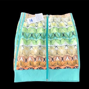 May include: A zip-up jacket with a butterfly pattern in shades of green, yellow, and orange. The jacket has a turquoise base and stripes down the sleeves. The Adidas logo is visible on a tag.