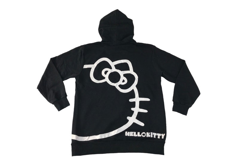 May include: Black hooded sweatshirt featuring a large white Hello Kitty graphic on the back. The design includes the iconic bow, face outline, and the text "HELLOKITTY" at the bottom. The sweatshirt has long sleeves and a hood.