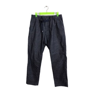 Op de afbeelding: Donkerblauwe spijkerbroek hangt aan een groene hanger. De broek heeft een taille met trekkoord en een klein logo aan de voorkant. De stof lijkt een mediumgewicht denim te zijn. De broek heeft een relaxte pasvorm.