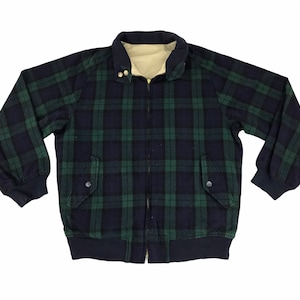 May include: A plaid jacket in navy blue and green with a cream-colored lining. The jacket has a zip-up front, two front pockets, and a ribbed hem and cuffs. The collar is navy blue.