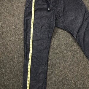 Op de afbeelding: Donkerblauwe vrijetijdsbroek met een tailleband met trekkoord en zijzakken. De broek wordt gemeten met een gele meetlint, met een lengte van ongeveer 99 cm. De stof heeft een subtiel textuurpatroon.