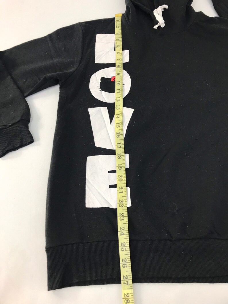 May include: Black hooded sweatshirt with the word "LOVE" printed vertically in large white letters. The "O" features a cartoon cat face. The sweatshirt has a drawstring hood and ribbed cuffs and hem. The length of the sweatshirt is approximately 28 inches.