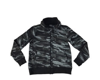 Könnte beinhalten: Eine schwarze und graue Jacke mit Reißverschluss und Camouflage-Muster und hohem Kragen.