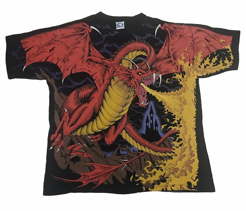 May include: Black t-shirt featuring a detailed illustration of a red dragon breathing fire. The dragon has large wings and sharp teeth. The background includes a castle silhouette and flames.