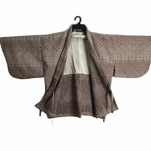 May include: A brown and white patterned Japanese kimono with a white lining. The kimono is open and hanging on a black hanger.