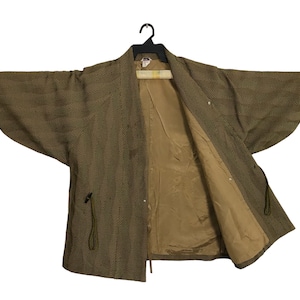 May include: A brown and green patterned kimono with a brown lining. The kimono has a tie closure and a long sleeve.