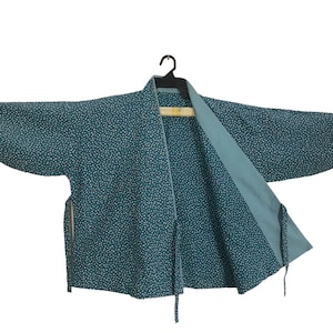 May include: A teal blue kimono with a white polka dot pattern. The kimono is open in the front and has a long tie.