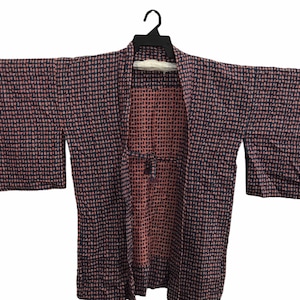 May include: A black and pink patterned kimono with a tie closure. The kimono has a geometric pattern of small squares.