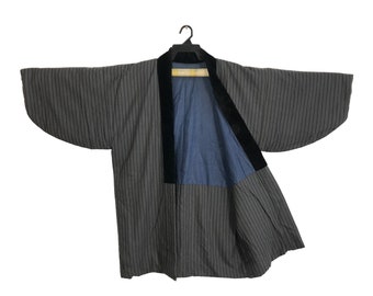 May include: A black and gray striped kimono with a black velvet trim and a blue lining. The kimono is open and hanging on a wooden hanger.