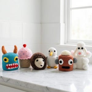 Puede incluir: Una colecci&oacute;n de seis animales de peluche de ganchillo de colores. La colecci&oacute;n incluye un monstruo azul, una magdalena rosa, un erizo marr&oacute;n, un ping&uuml;ino blanco, un robot marr&oacute;n y una oveja blanca. Cada animal tiene caracter&iacute;sticas &uacute;nicas.
