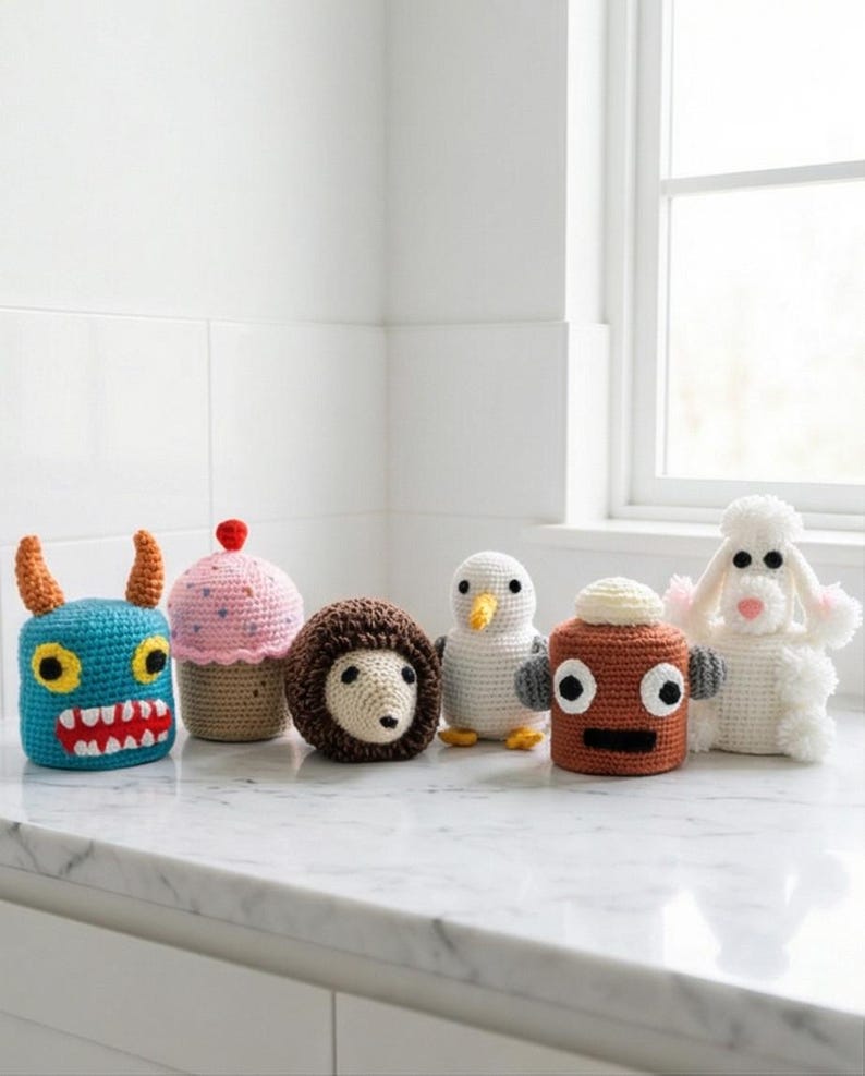 Puede incluir: Una colecci&oacute;n de seis animales de peluche de ganchillo de colores. La colecci&oacute;n incluye un monstruo azul, una magdalena rosa, un erizo marr&oacute;n, un ping&uuml;ino blanco, un robot marr&oacute;n y una oveja blanca. Cada animal tiene caracter&iacute;sticas &uacute;nicas.