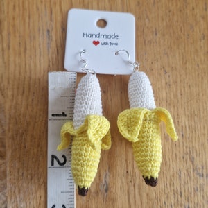 Crocheted banana earrings, yellow and white, approximately 2-3 inches long, hanging from silver ear wires.  The card attached reads 'Handmade with love'.