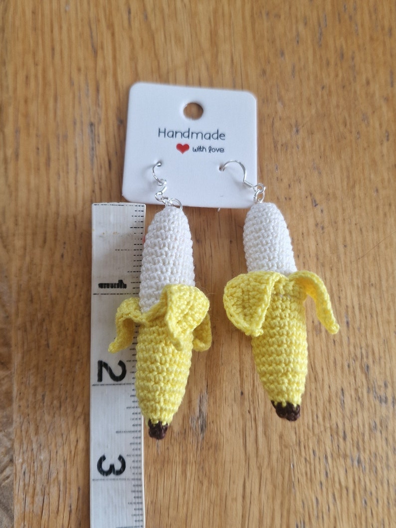 Crocheted banana earrings, yellow and white, approximately 2-3 inches long, hanging from silver ear wires.  The card attached reads 'Handmade with love'.