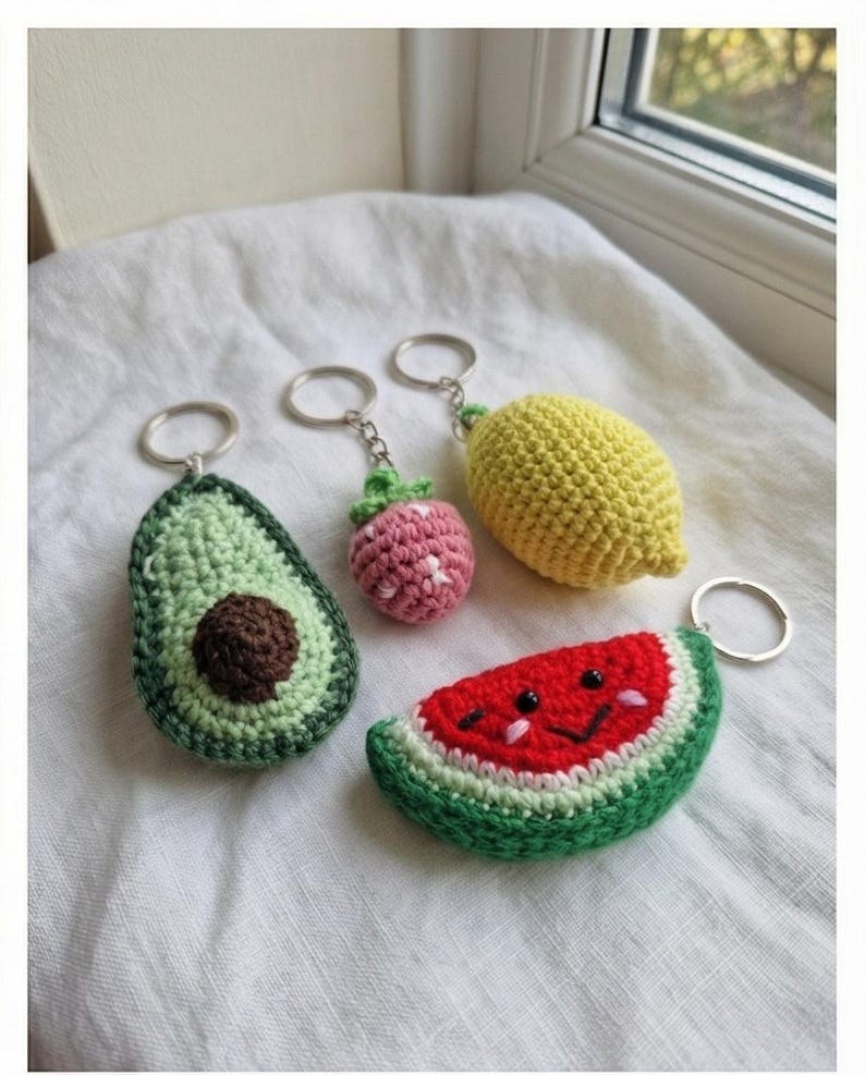 Peut inclure: Une collection de porte-cl&eacute;s crochet&eacute;s &agrave; la main en forme de fruits. Comprend un avocat, une fraise, un citron et une past&egrave;que. L'avocat est vert avec un noyau marron, la fraise est rose, le citron est jaune et la past&egrave;que a un visage souriant.