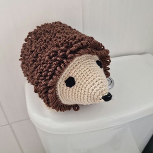 Puede incluir: Una funda de papel higi&eacute;nico de ganchillo con forma de erizo. El erizo tiene una cara beige claro, ojos negros y una nariz negra. El cuerpo es marr&oacute;n con un aspecto texturizado y puntiagudo. Dise&ntilde;ado para cubrir un rollo de papel higi&eacute;nico est&aacute;ndar.
