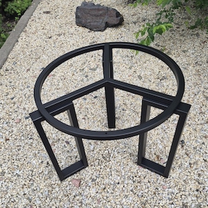 Op de afbeelding: Een zwart metalen tafelonderstel met een cirkelvormig bovenframe en een interne steunstructuur met drie spaken. Het onderstel wordt ondersteund door drie rechthoekige poten, elk geconstrueerd uit vierkante metalen buizen.