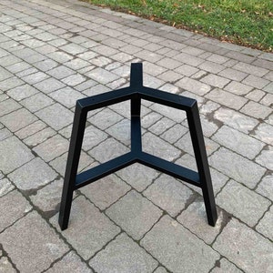 May include: Black metal table base with a triangular design. The base has three legs that meet at a point in the centre.