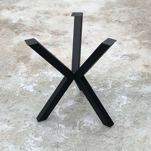May include: Black metal table base with a starburst design. The base has four legs that meet in the center and extend outwards to form a star shape.