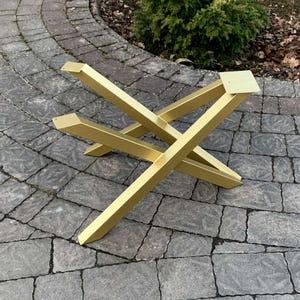 May include: Gold metal table base with a criss-cross design. The base is made of four pieces of metal that are welded together to form a sturdy and stylish base.