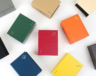 May include: Nine small, square, fabric-covered boxes in various colors, including gray, green, red, orange, yellow, blue, and black. Each box has a different gold-colored symbol on the front.