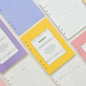 May include: A set of six colorful, hole-punched paper refills for a planner or journal. The refills are labeled "Monthly", "Weekly", "Daily", and "To-Do List".