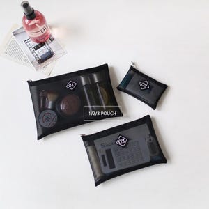 May include: Three black mesh pouches with zipper closures. The pouches are labeled 01, 02, and 03. The pouches are filled with various items, including a bottle of spray, a calculator, and makeup.