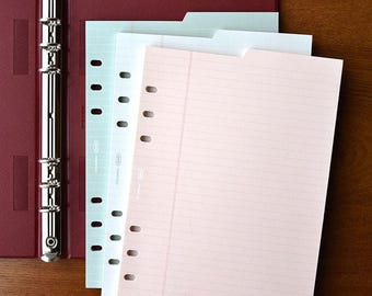 May include: A red binder with three different colored paper refills. The refills are lined and have holes for a binder. The paper is light blue, white, and pink.
