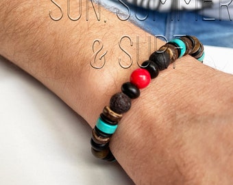 Pode incluir: Um bracelete de contas com rocha de lava preta, madeira marrom, turquesa e contas vermelhas. O bracelete está no pulso de uma pessoa.