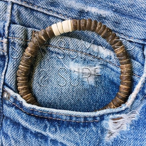 May include: A brown and white wooden beaded bracelet with the text "SUN SUMMER & SURF" in the background.