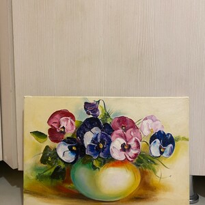 May include: A painting of a bouquet of purple, pink, and white pansies in a green vase. The pansies are arranged in a loose, natural style, and the vase is simple and elegant. The background is a soft yellow.