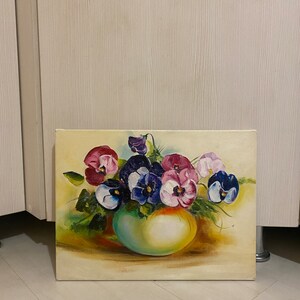 May include: A painting of a bouquet of purple, pink, and blue pansies in a green vase. The pansies are arranged in a cluster and the vase is sitting on a yellow surface.