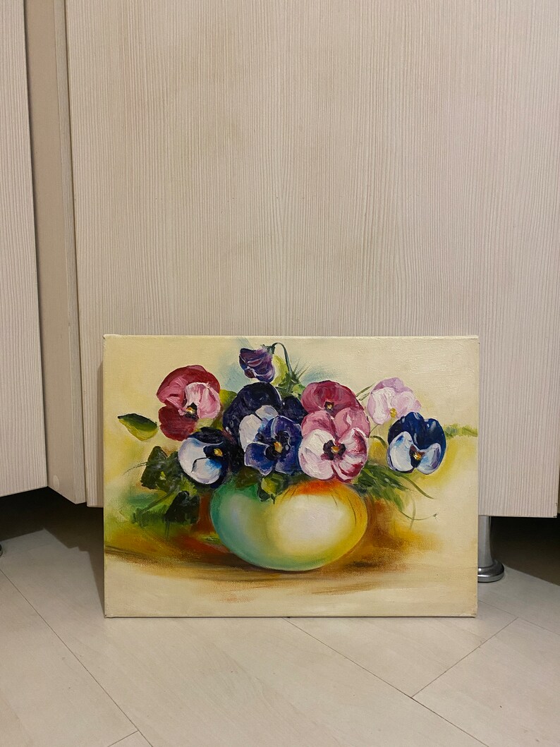 May include: A painting of a bouquet of purple, pink, and blue pansies in a green vase. The pansies are arranged in a cluster and the vase is sitting on a yellow surface.
