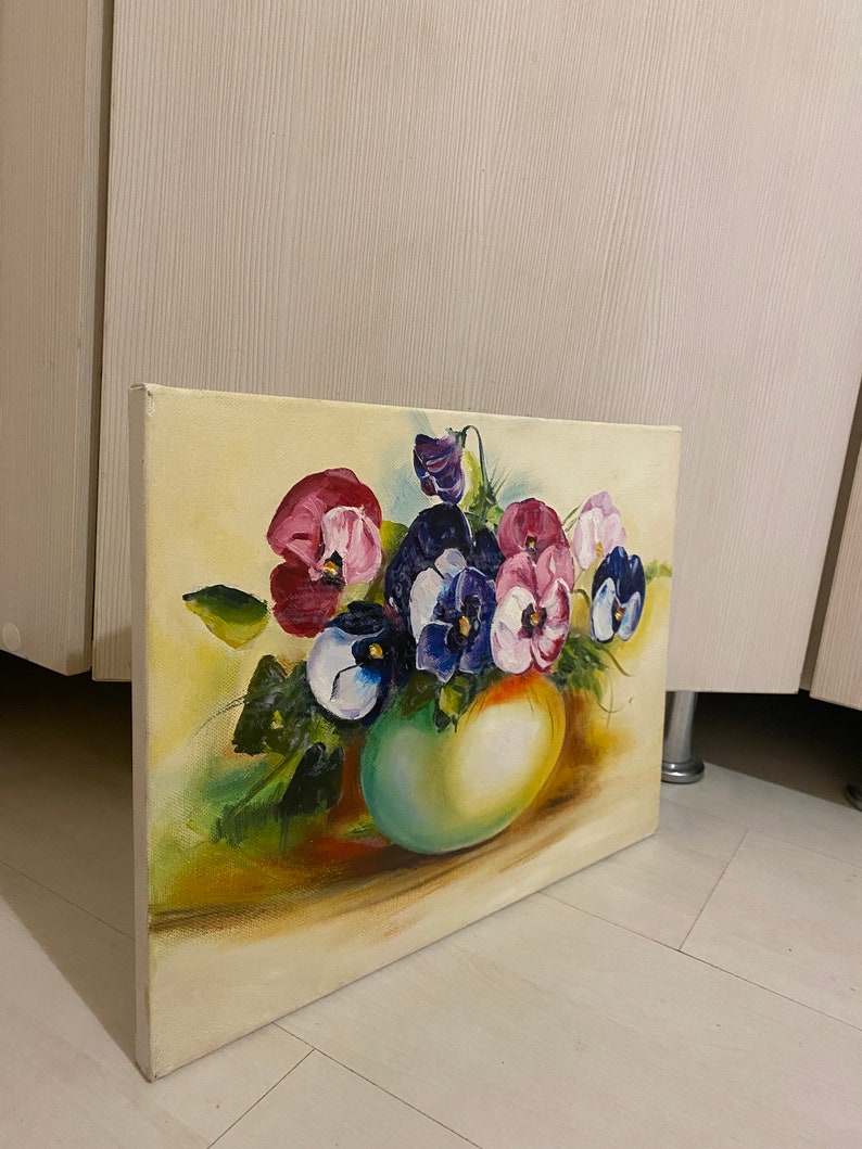 May include: A painting of a bouquet of purple, pink, and white pansies in a green vase. The pansies are arranged in a loose, natural style, and the vase is a simple, rounded shape. The background is a soft yellow.