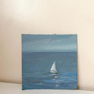 May include: A painting of a sailboat on a blue sea with a light blue sky in the background.