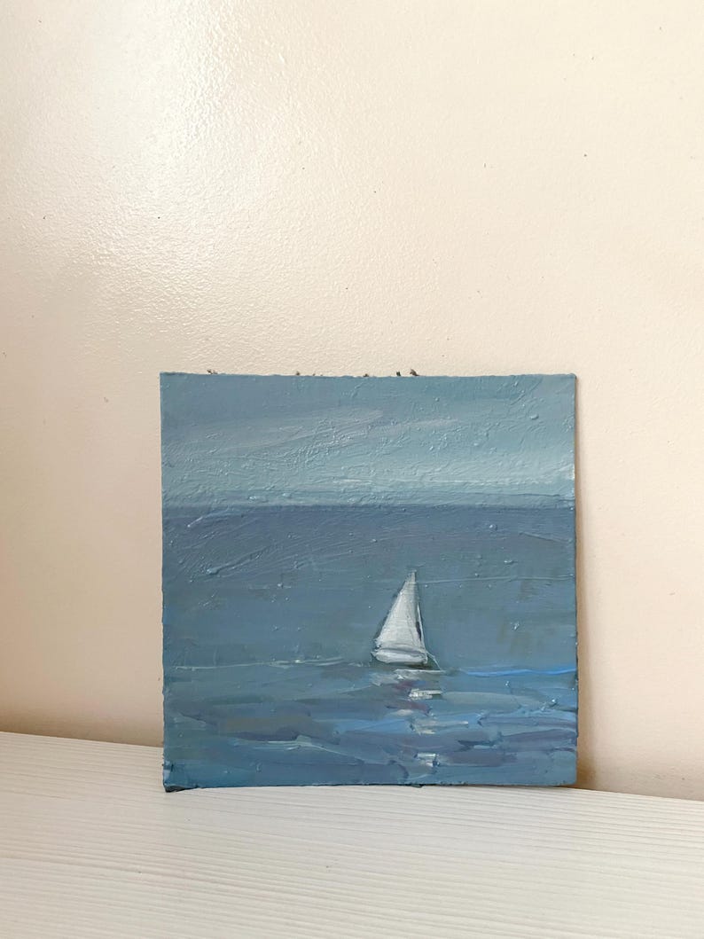 May include: A painting of a sailboat on a blue sea with a light blue sky in the background.