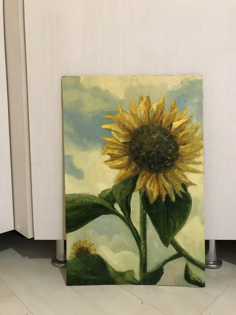 May include: A painting of a sunflower with yellow petals and a dark brown center. The sunflower is against a light blue and white cloudy sky. The sunflower is painted in a realistic style.